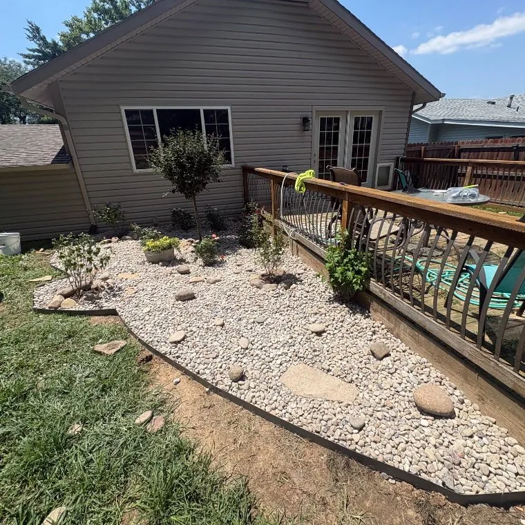 Finished river-rock bed with new shrubs and a cut edge, Lake St. Louis